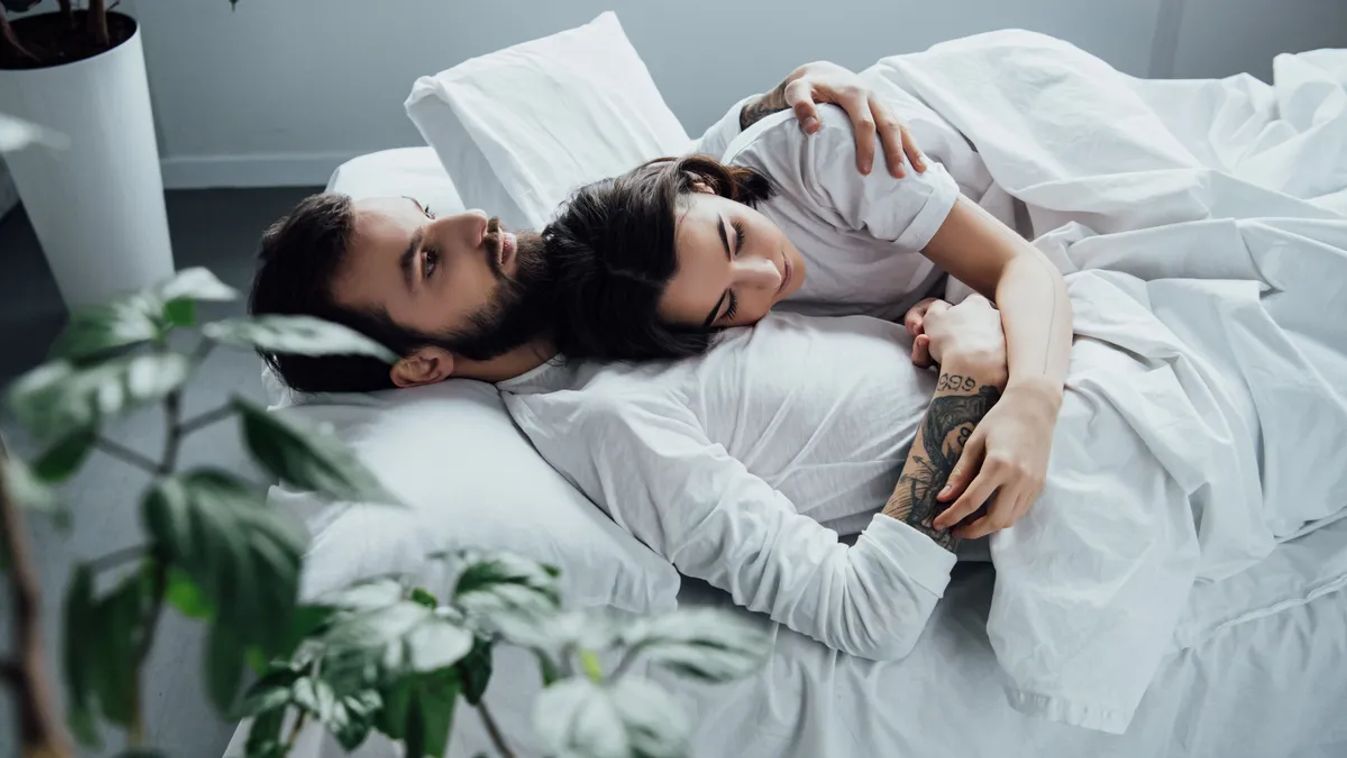 Beautiful,Young,Couple,In,Pajamas,Embracing,While,Lying,In,Bed