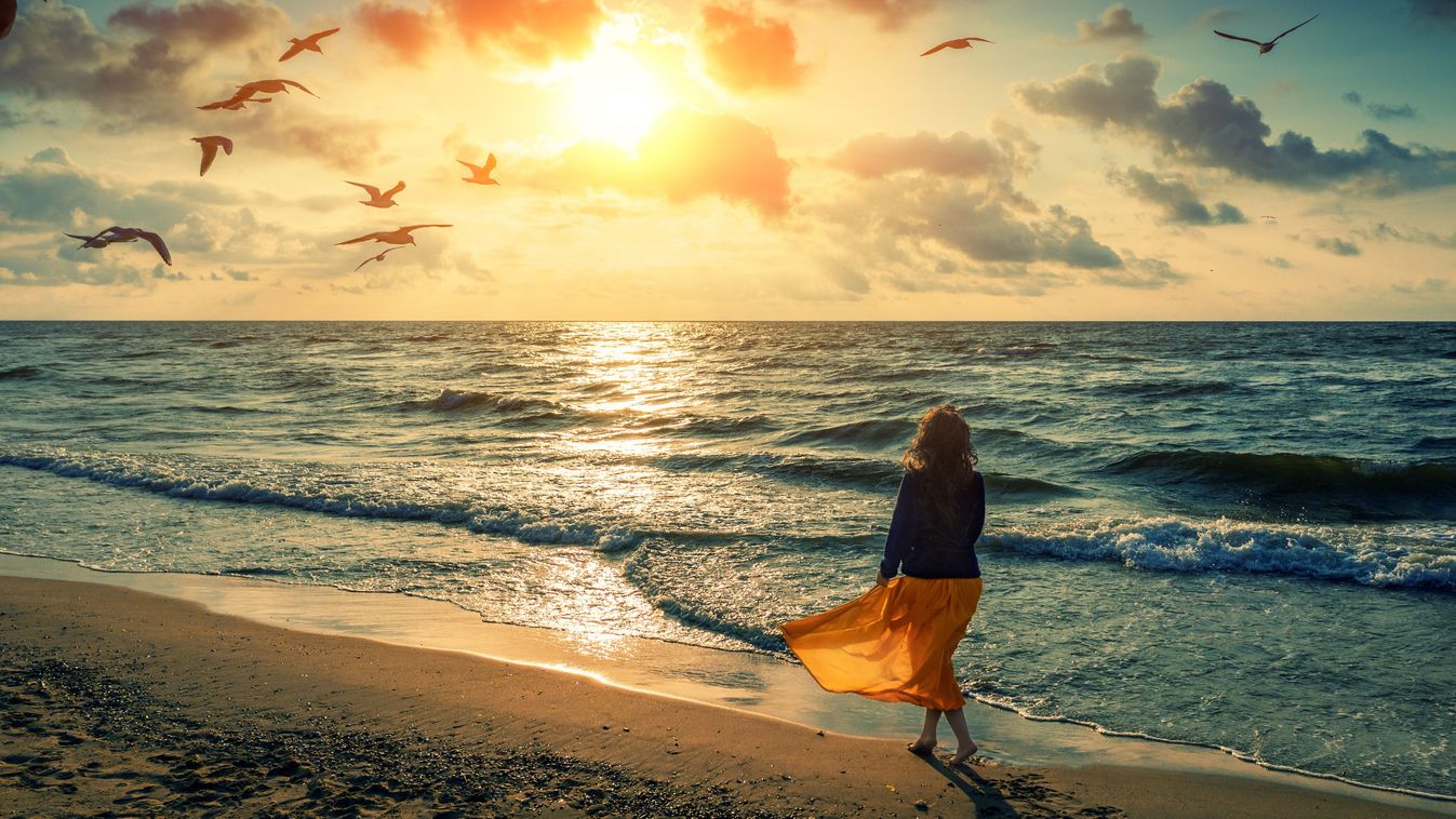 napfelkelte a tengerparton, fiatal nő sétál a napfelkeltében