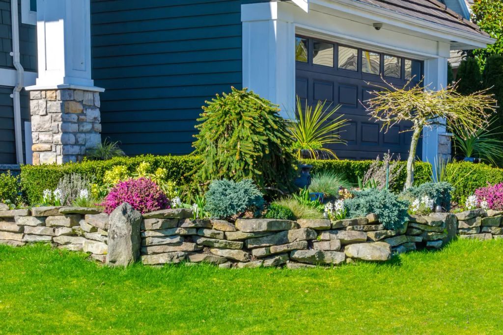 Nicely,Trimmed,Bushes,,Flowers,And,Stones,In,Front,Of,The