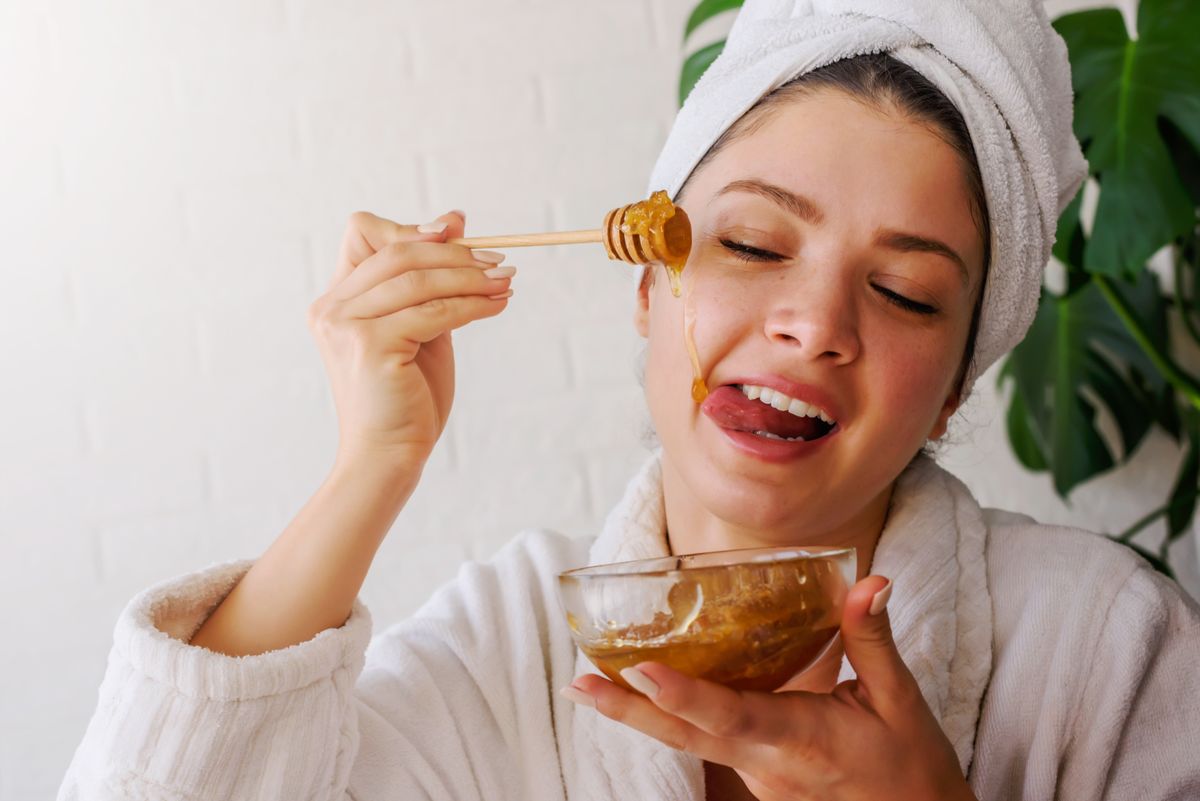 Portrait,Of,Young,Woman,Wearing,Bathrobe,At,Home,Eating,Honey.
méz