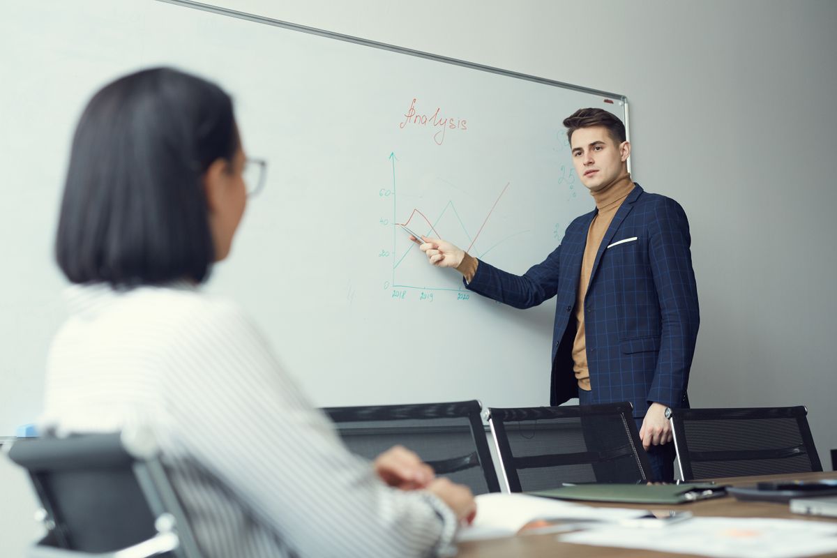 Young,Businessman,Standing,Near,The,Whiteboard,And,Pointing,At,It