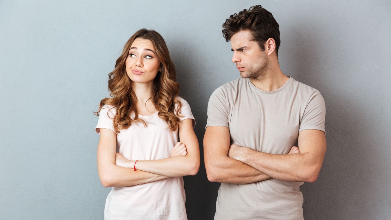 Disappointed,Young,Couple,Standing,With,Arms,Folded,Over,Gray,Wall
