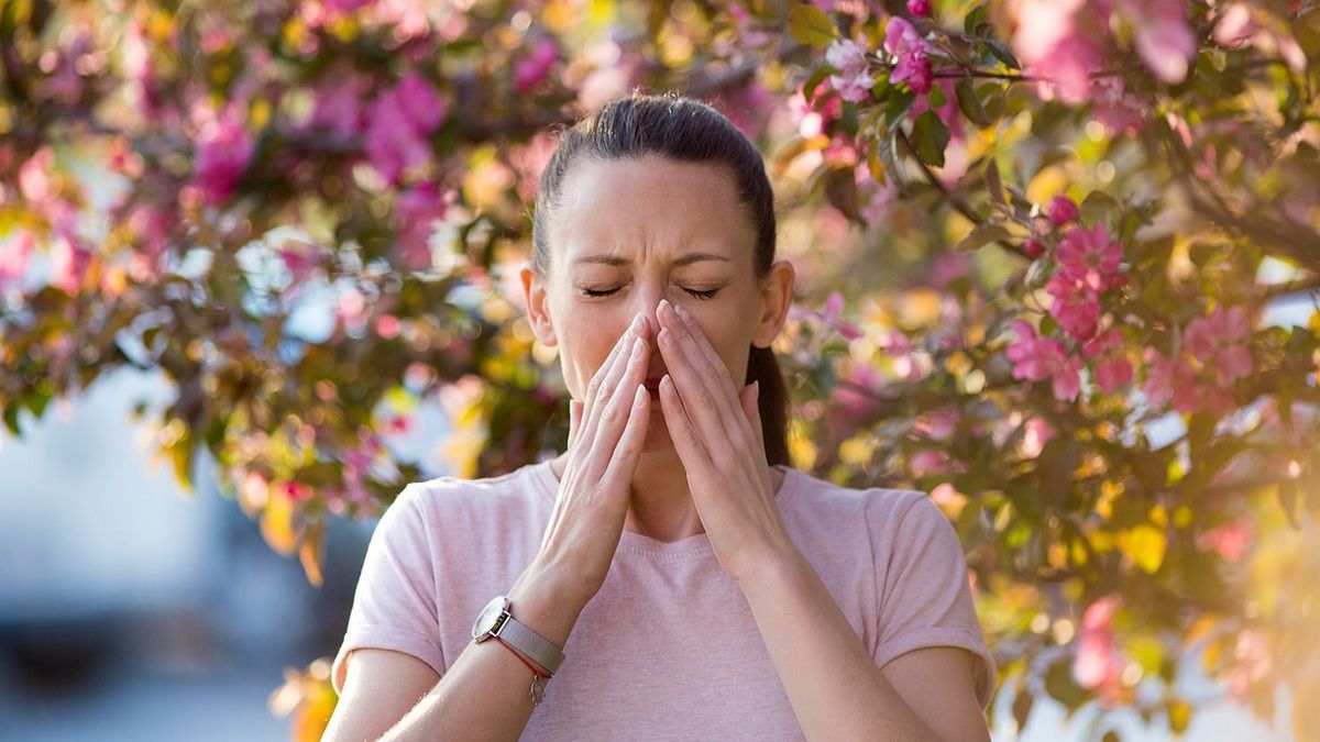 Young,Pretty,Woman,Sneezing,In,Front,Of,Blooming,Tree.,Spring