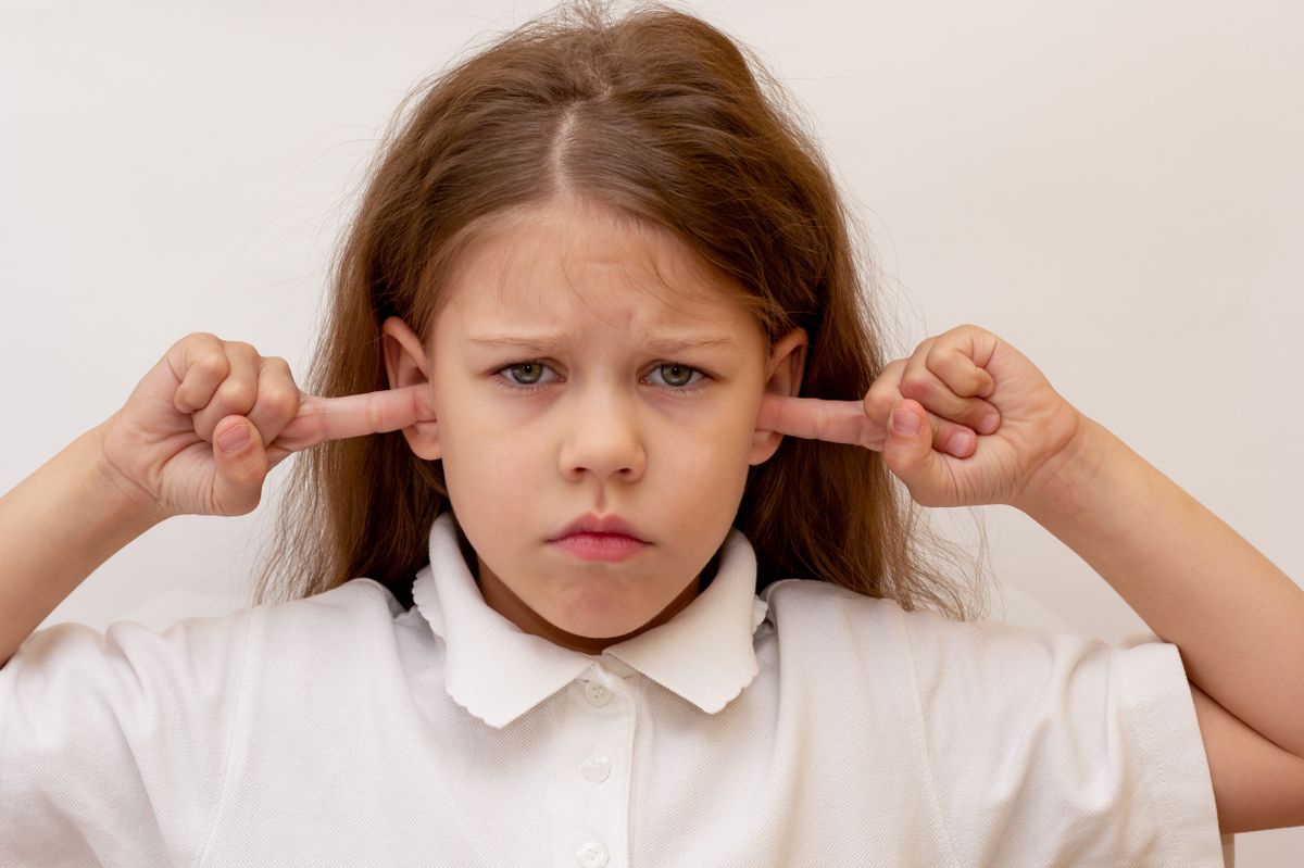 Portrait,Of,Caucasian,Child,Close,Ears,By,Fingers,On,White