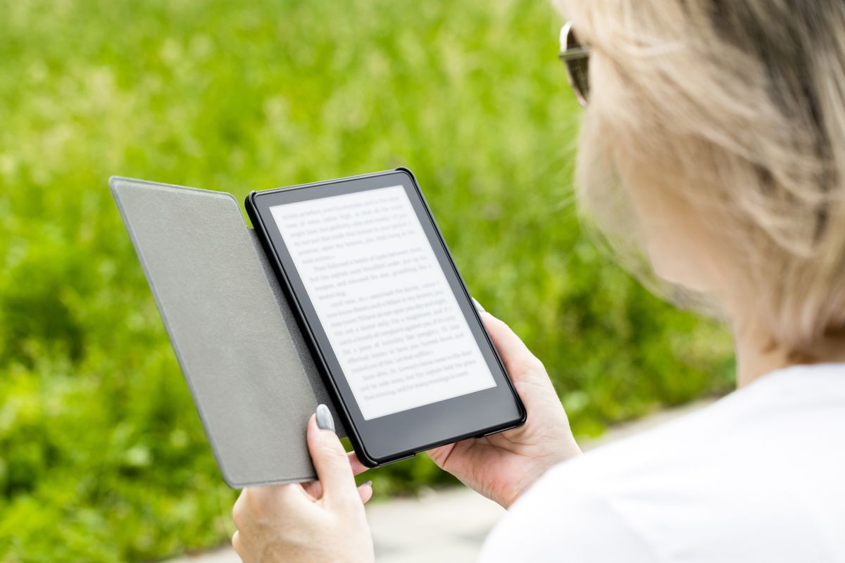 Woman,Reading,An,E-book,Sitting,On,A,Park,Bench.,Man