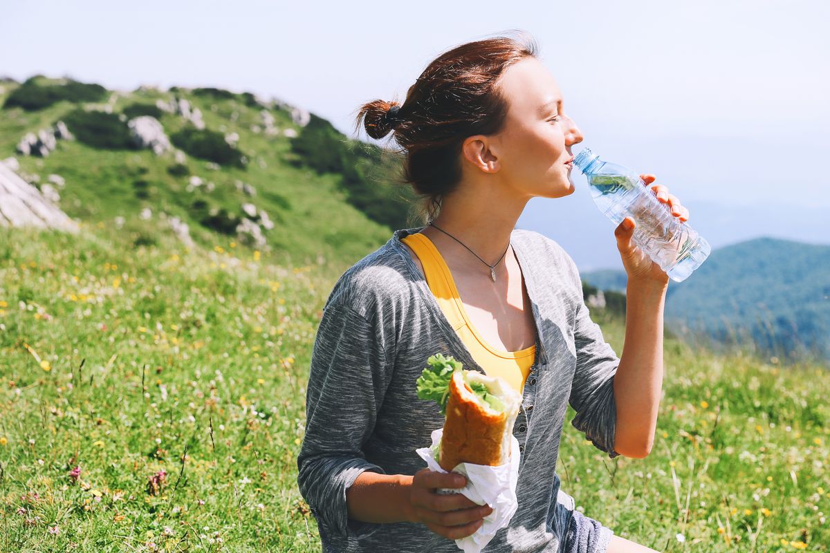 Beautiful,Young,Woman,Drinking,Still,Water,And,Eating,Vegetarian,Sandwich