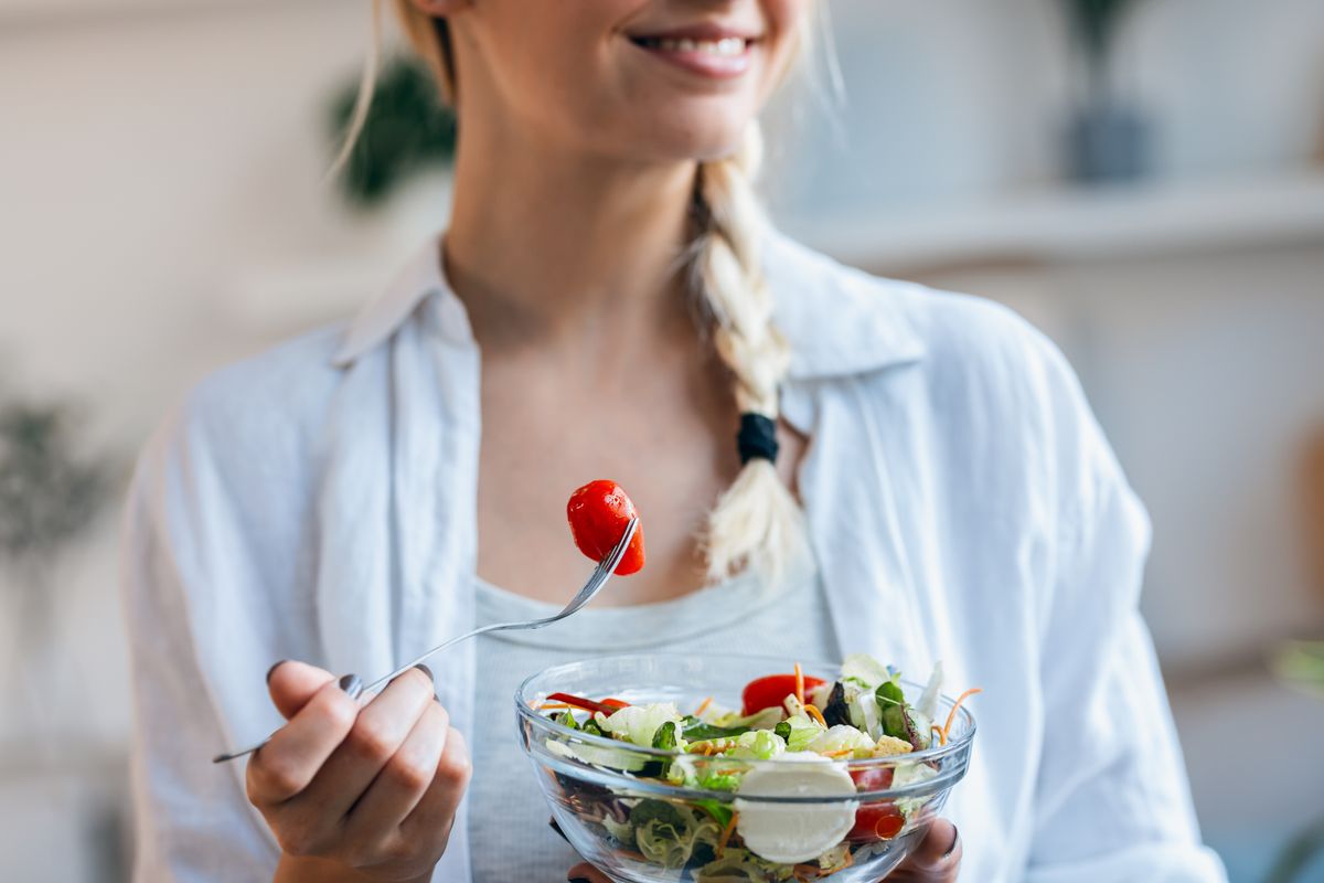 Closeup,Of,Smiling,Woman,Eating,Healthy,Salad,While,Sitting,On