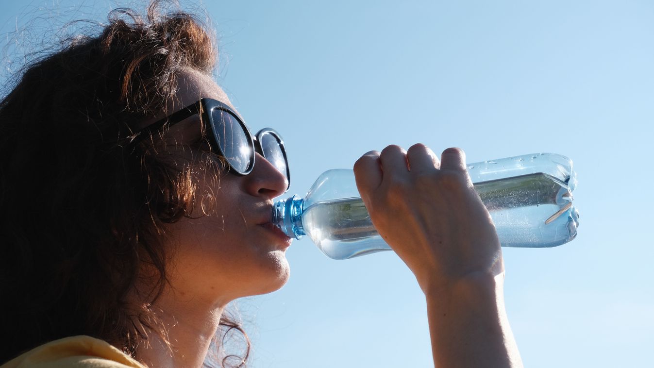 Girl,With,Glasses,Drinks,Water,From,A,Bottle,In,Hot