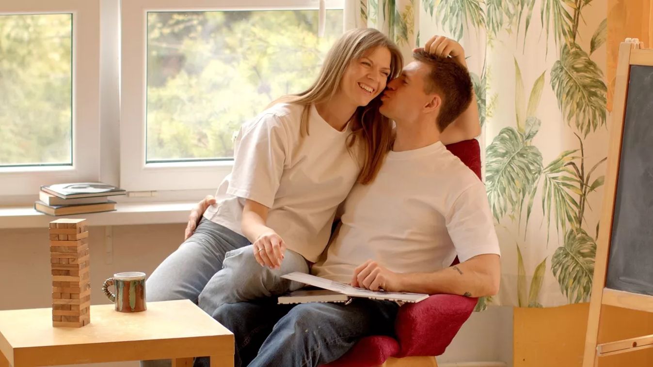 Couple,Kisses,While,Sitting,In,A,Chair,At,Home.,Young