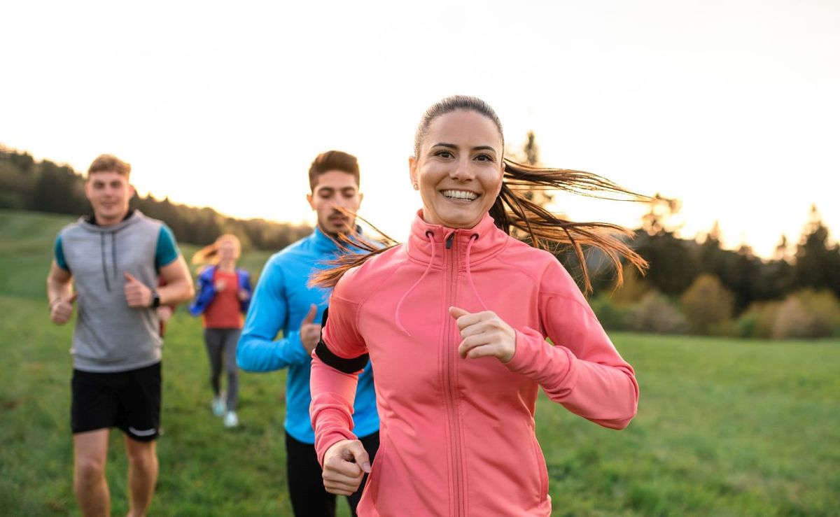 A large group of people cross country running in nature.