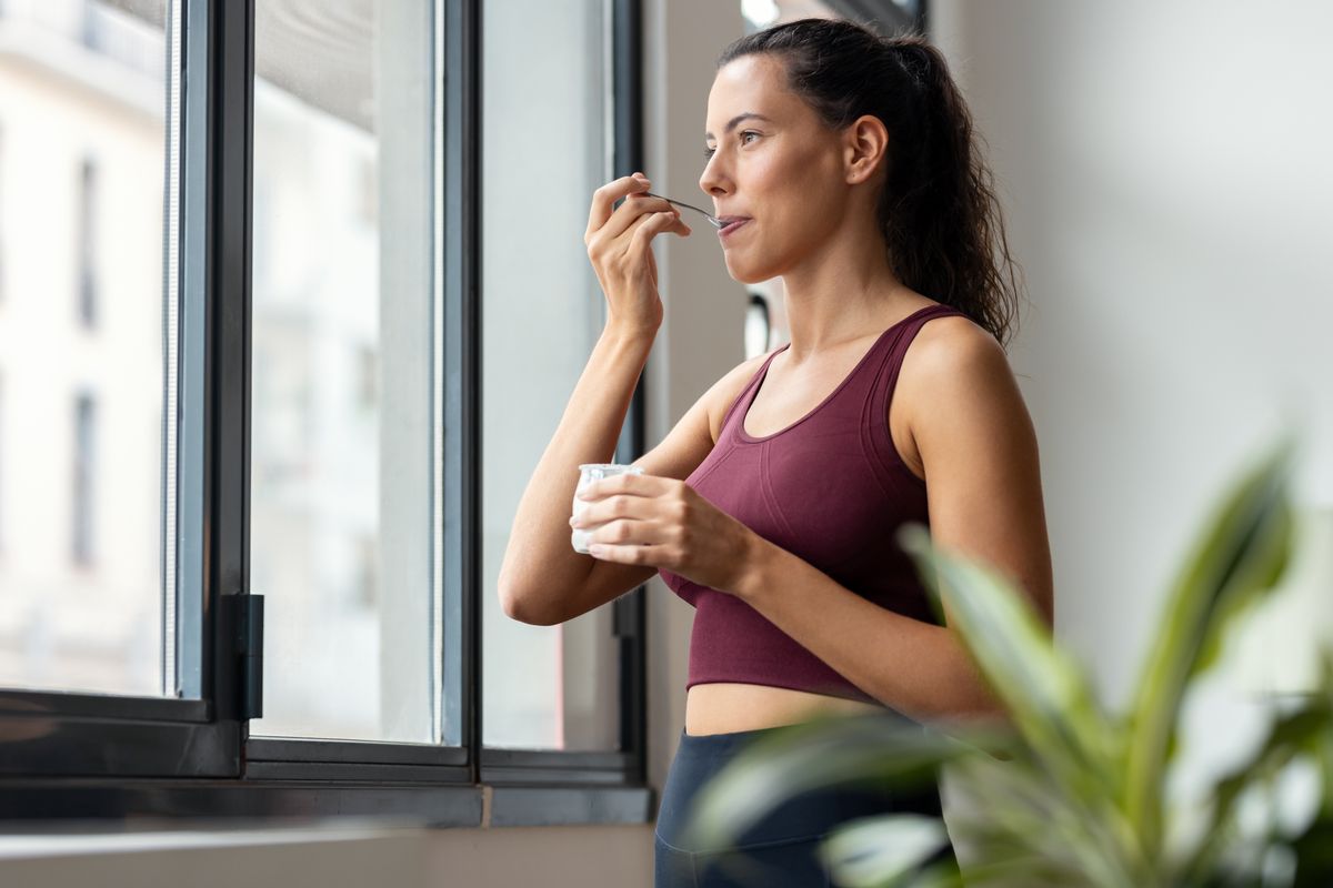 Shot,Of,Beautiful,Sporty,Woman,Eating,Yogurt,While,Looking,Forwards