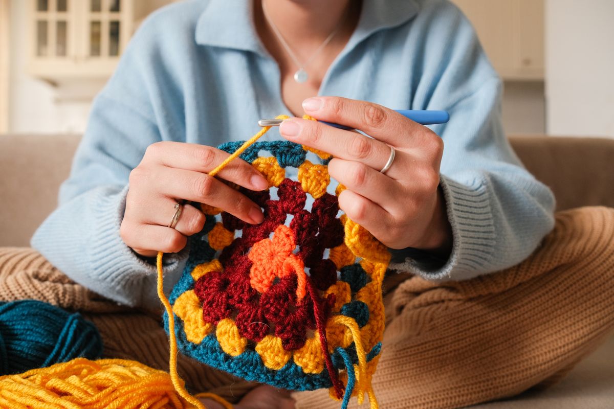 Young,Woman,Knitting,Crocheting,With,Colored,Yarn,Granny,Square,At, kreatív hobbi kötés