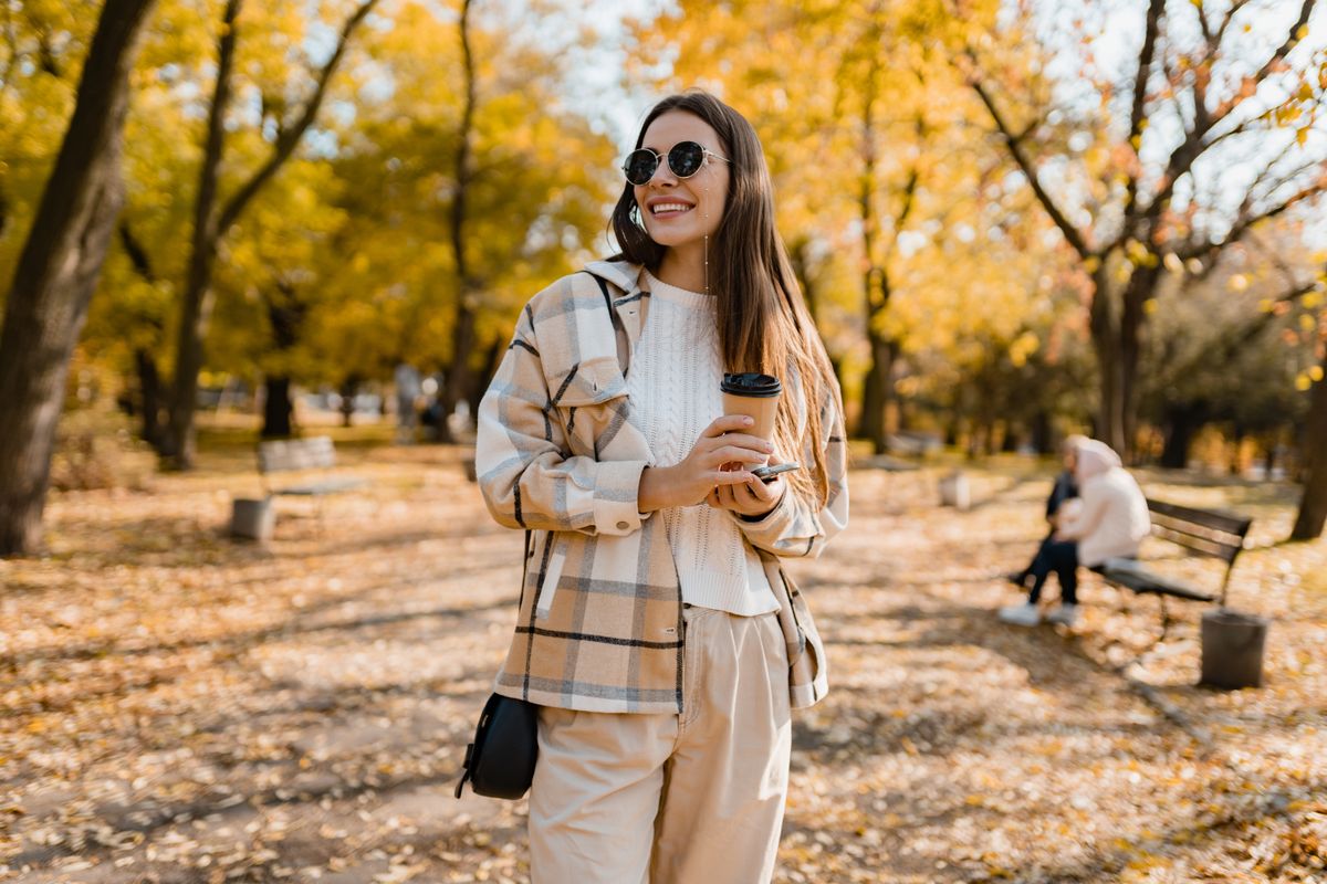 Attractive,Young,Woman,Walking,In,Autumn,Park,With,Coffee,Wearing