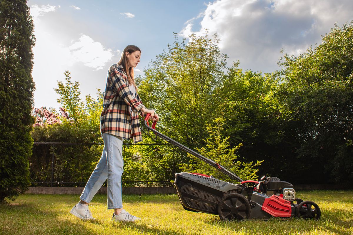 Female,Gardener,Working,In,Autumn,,Cutting,Grass,In,Backyard.,Concept