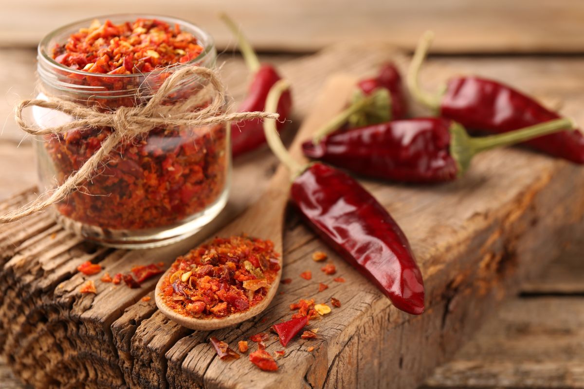 Chili,Pepper,Flakes,And,Pods,On,Wooden,Table,,Closeup