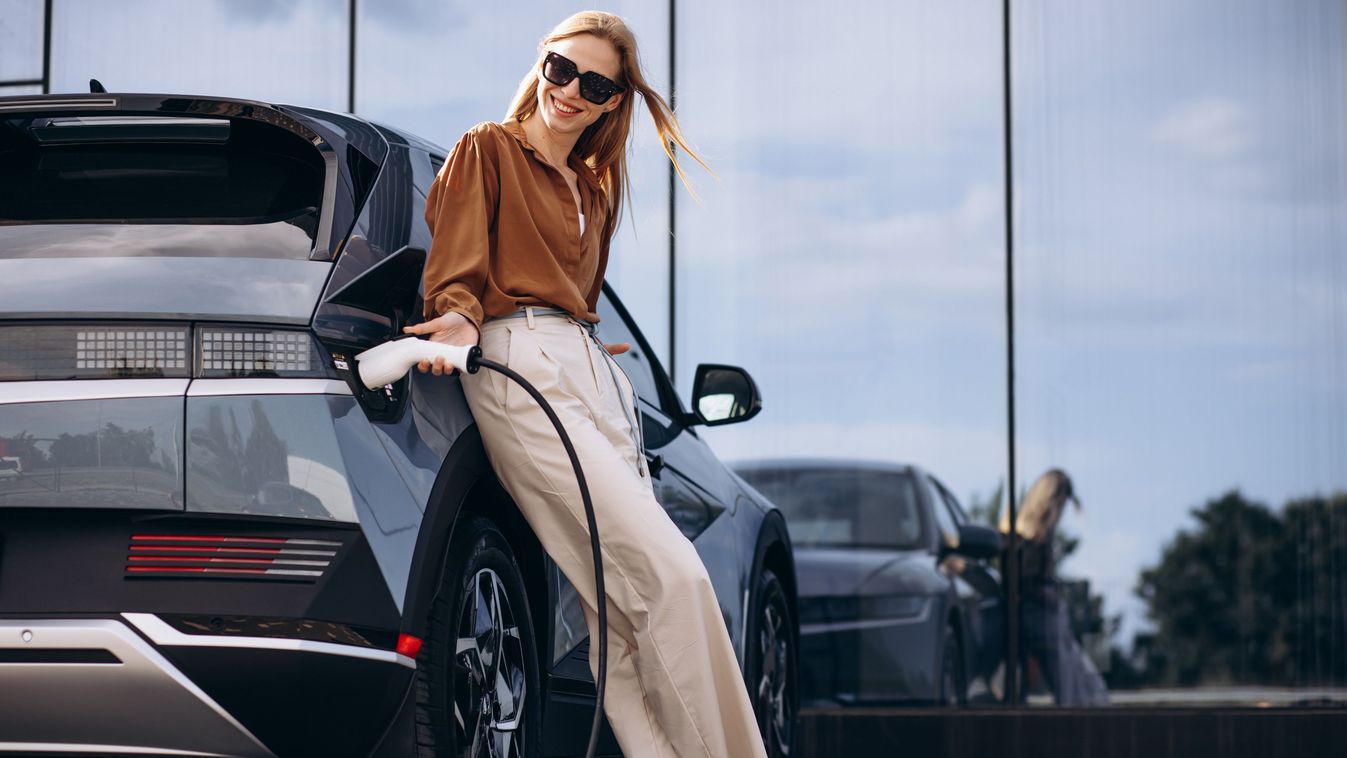 Woman,Charging,Electric,Car,And,Holding,Charger