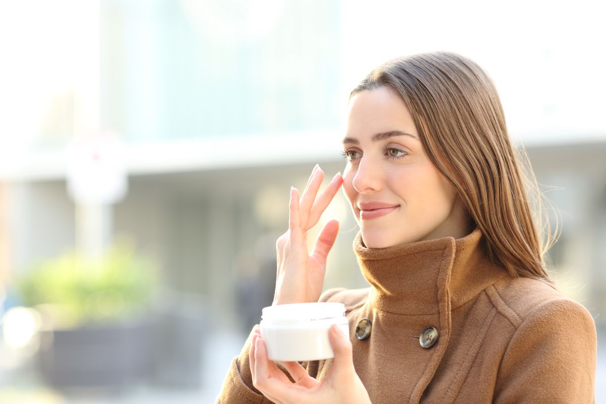 Satisfied,Woman,Applying,Mousturizer,Cream,On,Her,Face,In,Winter