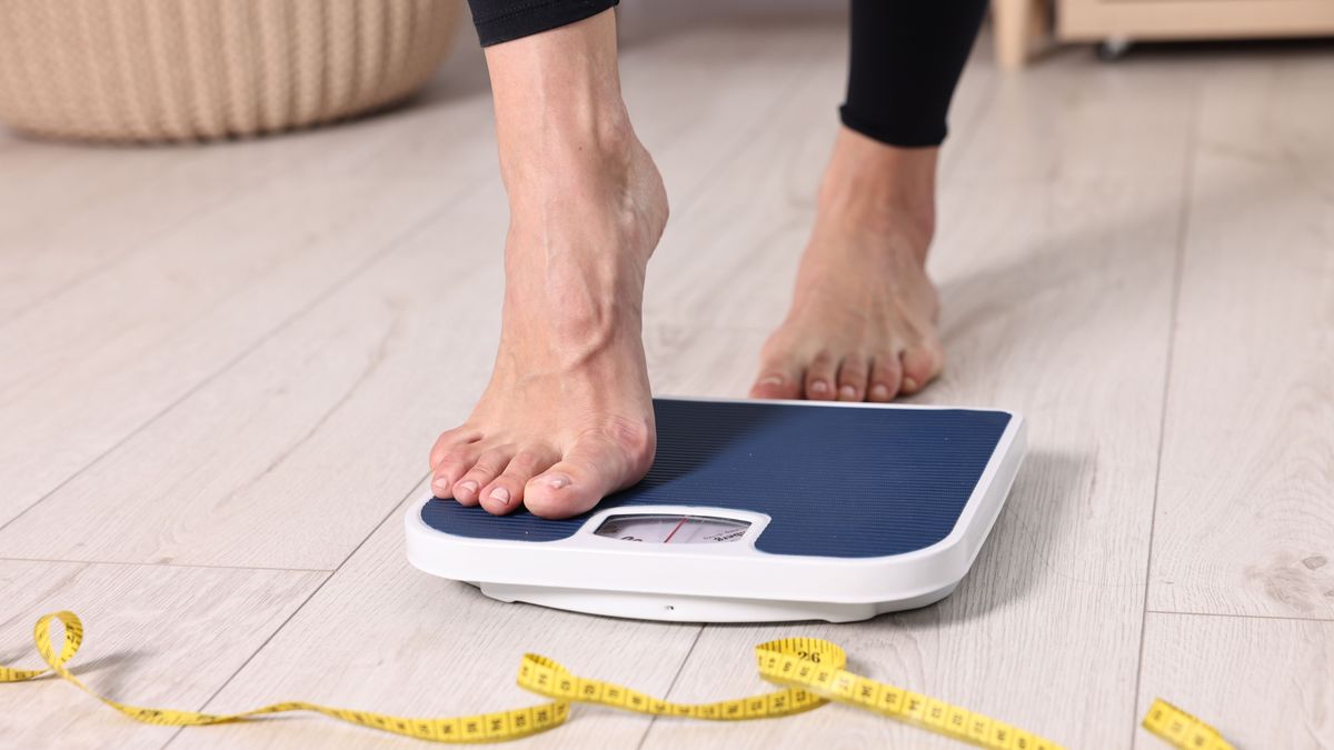 Woman,Stepping,On,Floor,Scale,And,Measuring,Tape,At,Home,
mérleg fogyás diéta