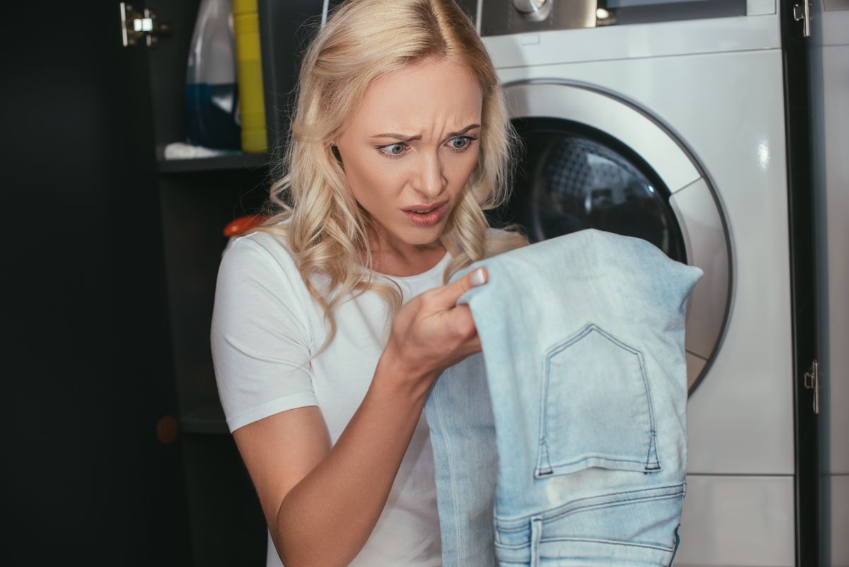 Shocked,Housewife,Looking,At,Jeans,While,Standing,Near,Washing,Machine