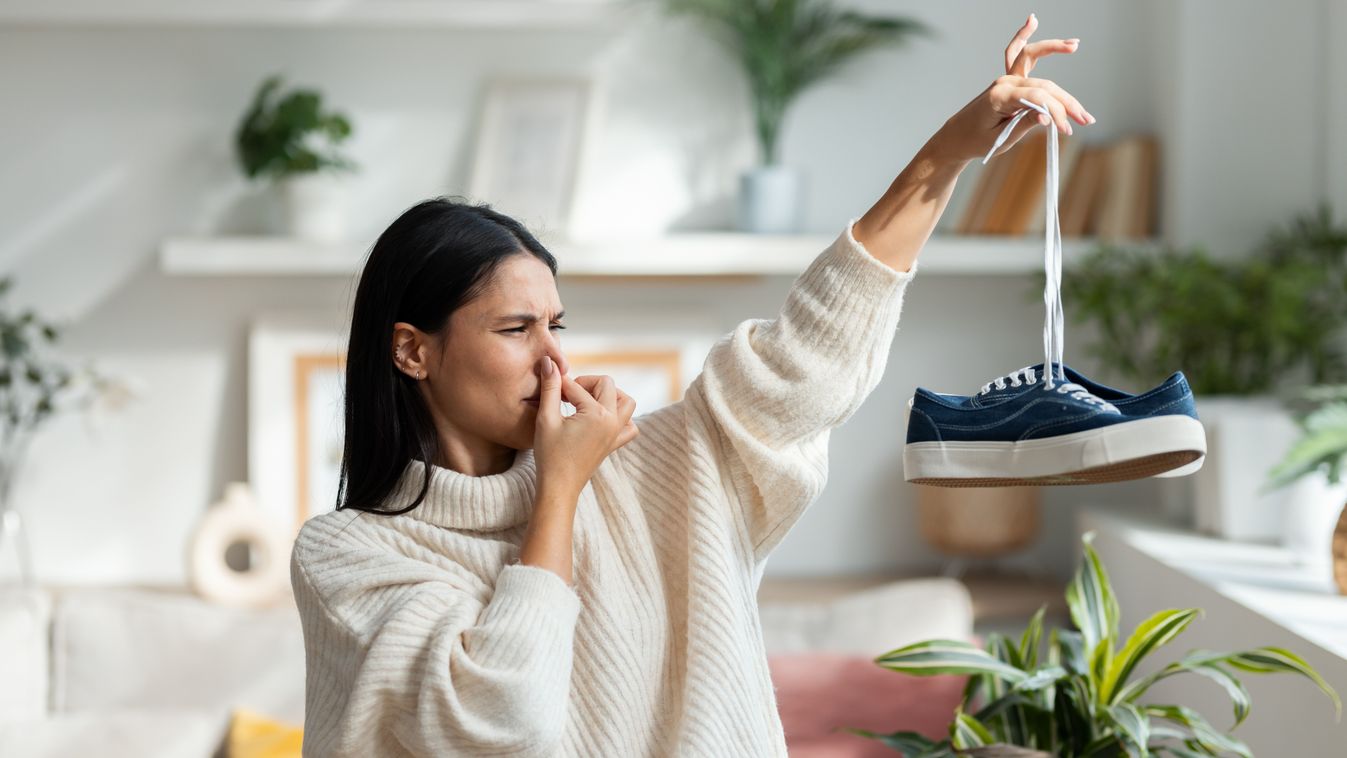 Shot,Of,Disgusted,Beautiful,Woman,Holding,Stinky,Shoes,In,The