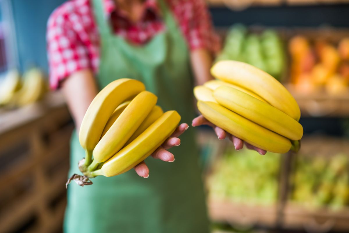 Worker,In,Fruits,And,Vegetables,Shop,Is,Holding,Bananas.,Close