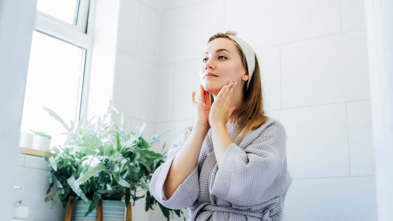 Young,Woman,In,Bathrobe,Looking,In,Mirror,And,Doing,Manual