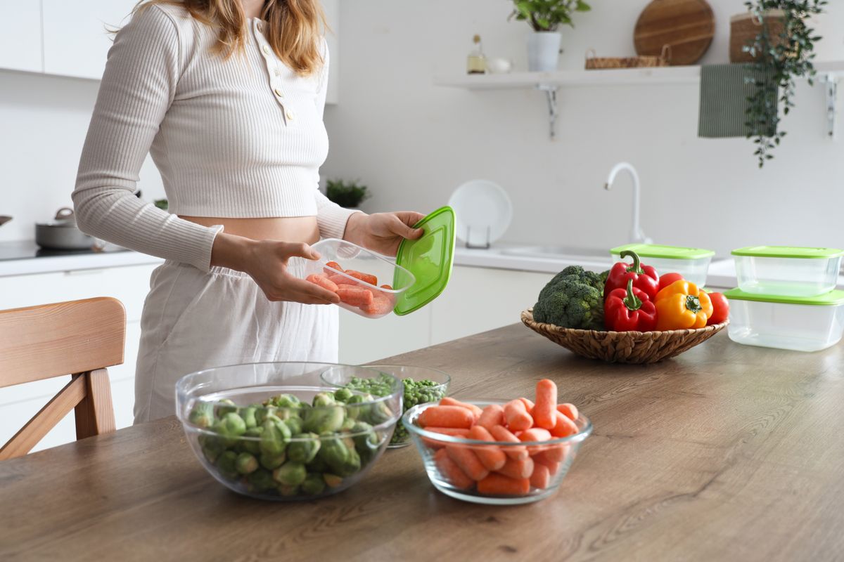 Woman,With,Frozen,And,Fresh,Vegetables,At,Table,In,Kitchen