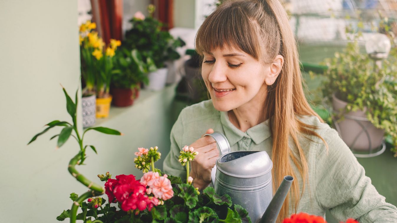 Happy,Woman,Gardener,Watering,Plants,Sitting,At,Table,In,Terrace