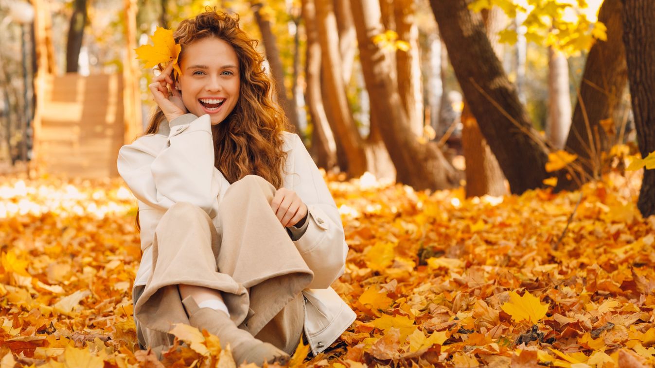 Smiling,Young,Woman,Sitting,On,The,Autumn,Foliage,On,The