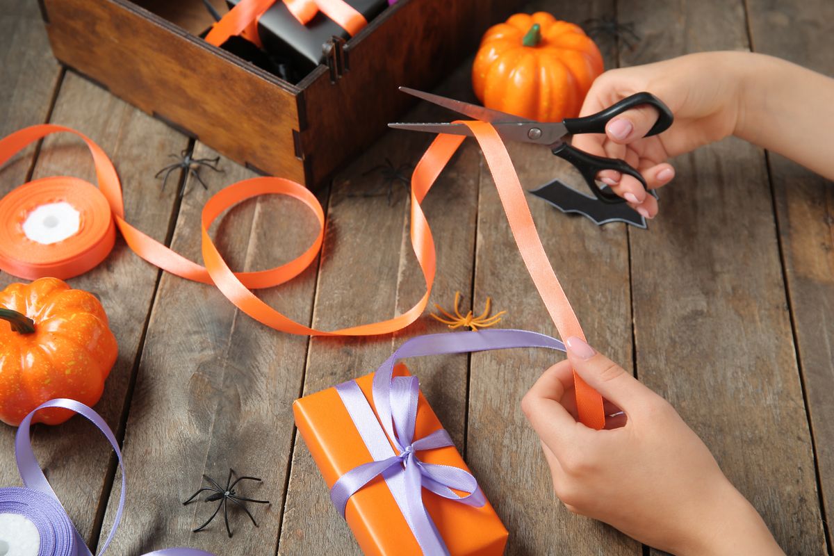 Woman,Cutting,Ribbon,For,Halloween,Gift,On,Brown,Wooden,Background