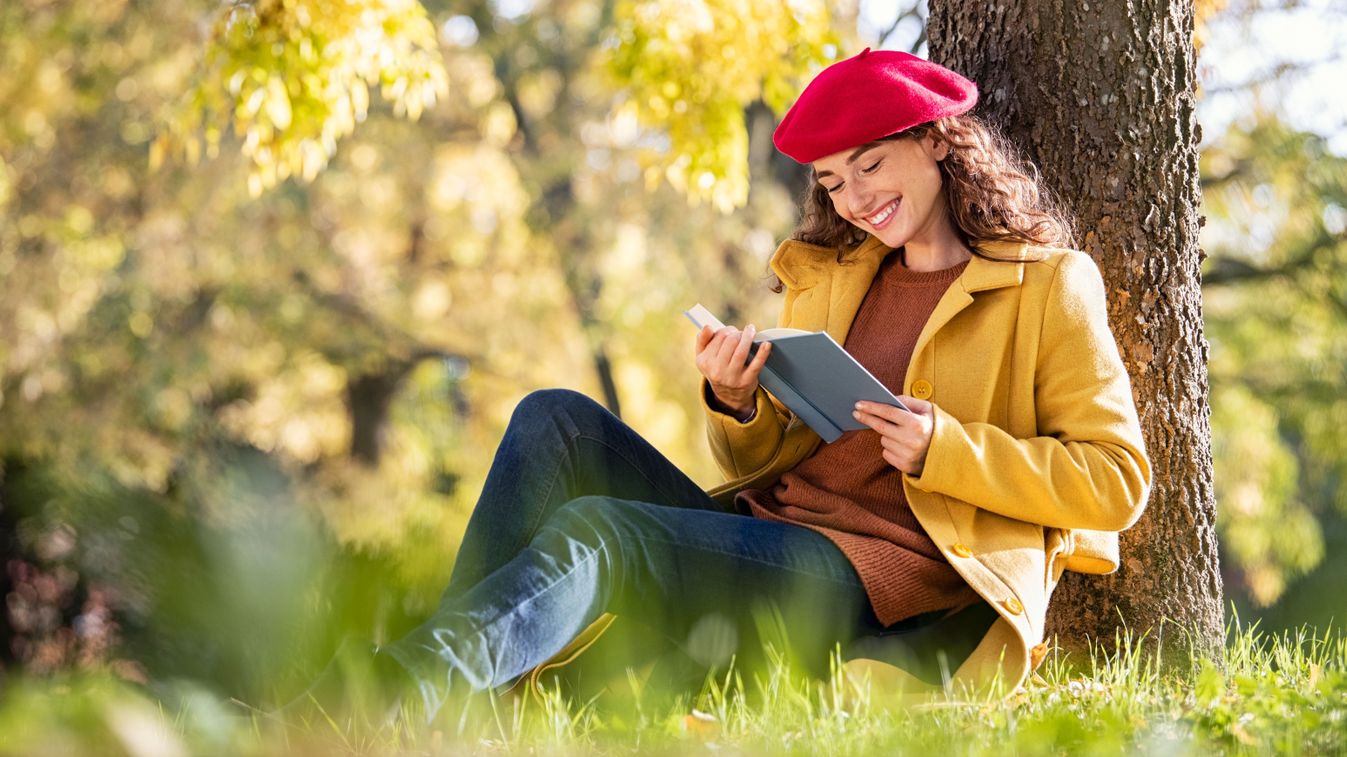 Beautiful,Young,Woman,Sitting,On,Fallen,Autumn,Leaves,In,A