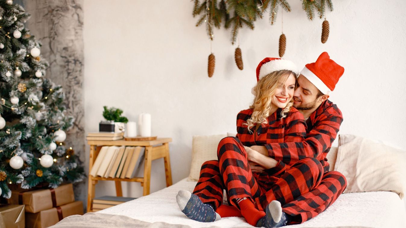 Couple,Wearing,Christmas,Plaid,Red,Pajamas,Hugging,On,The,Bed