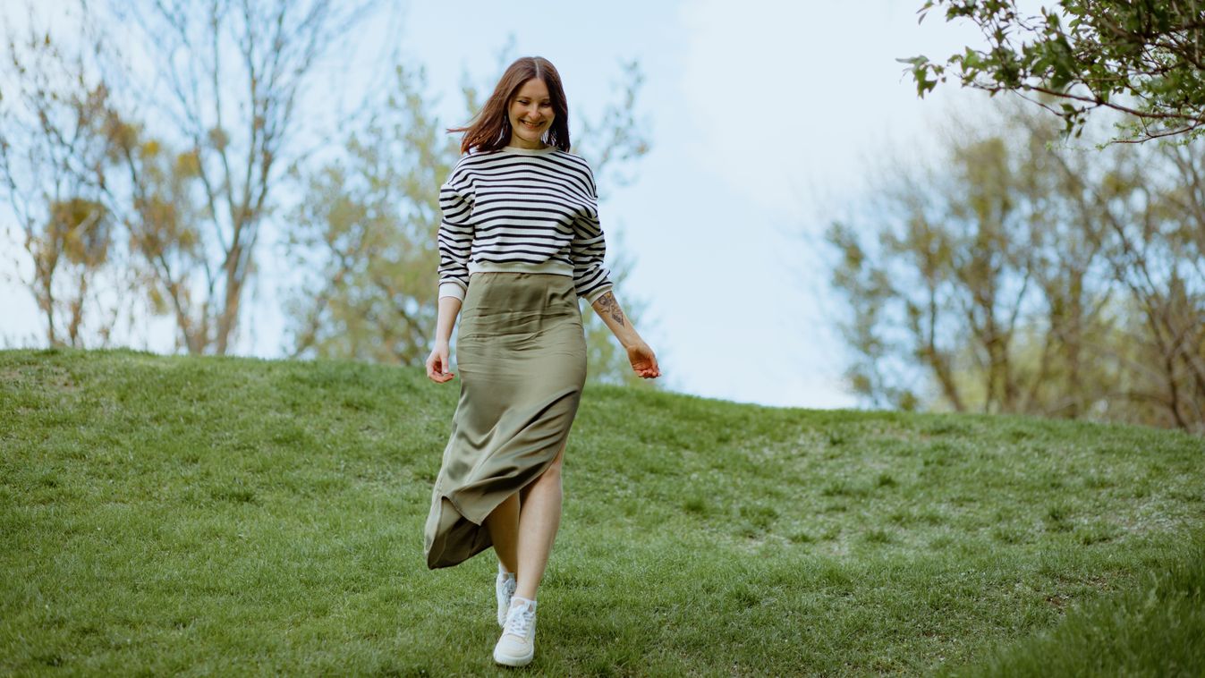 Beautiful mature woman walking down green hill smiling on sunny day