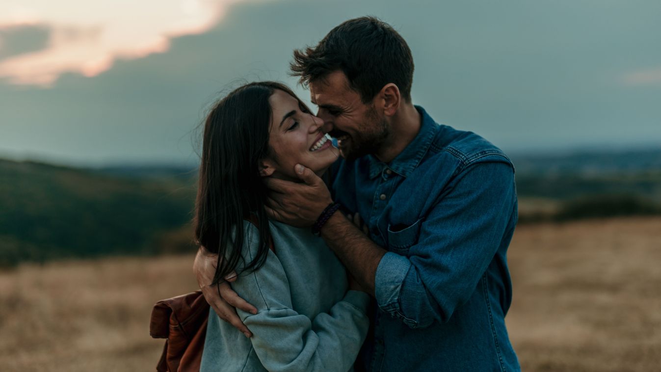 Traveling,Couple,Standing,Outdoors,Together,And,Laughing,During,An,Evening