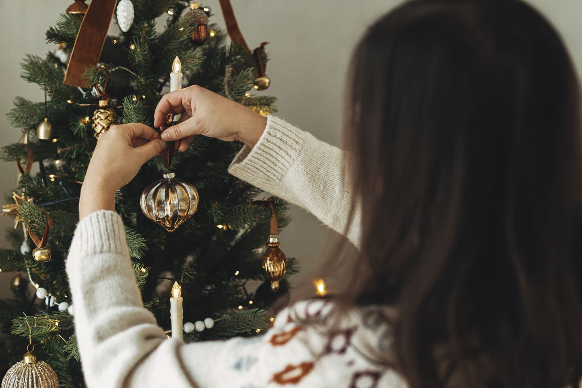 Decorating,Christmas,Tree,With,Stylish,Bauble.,Hands,In,Cozy,Sweater