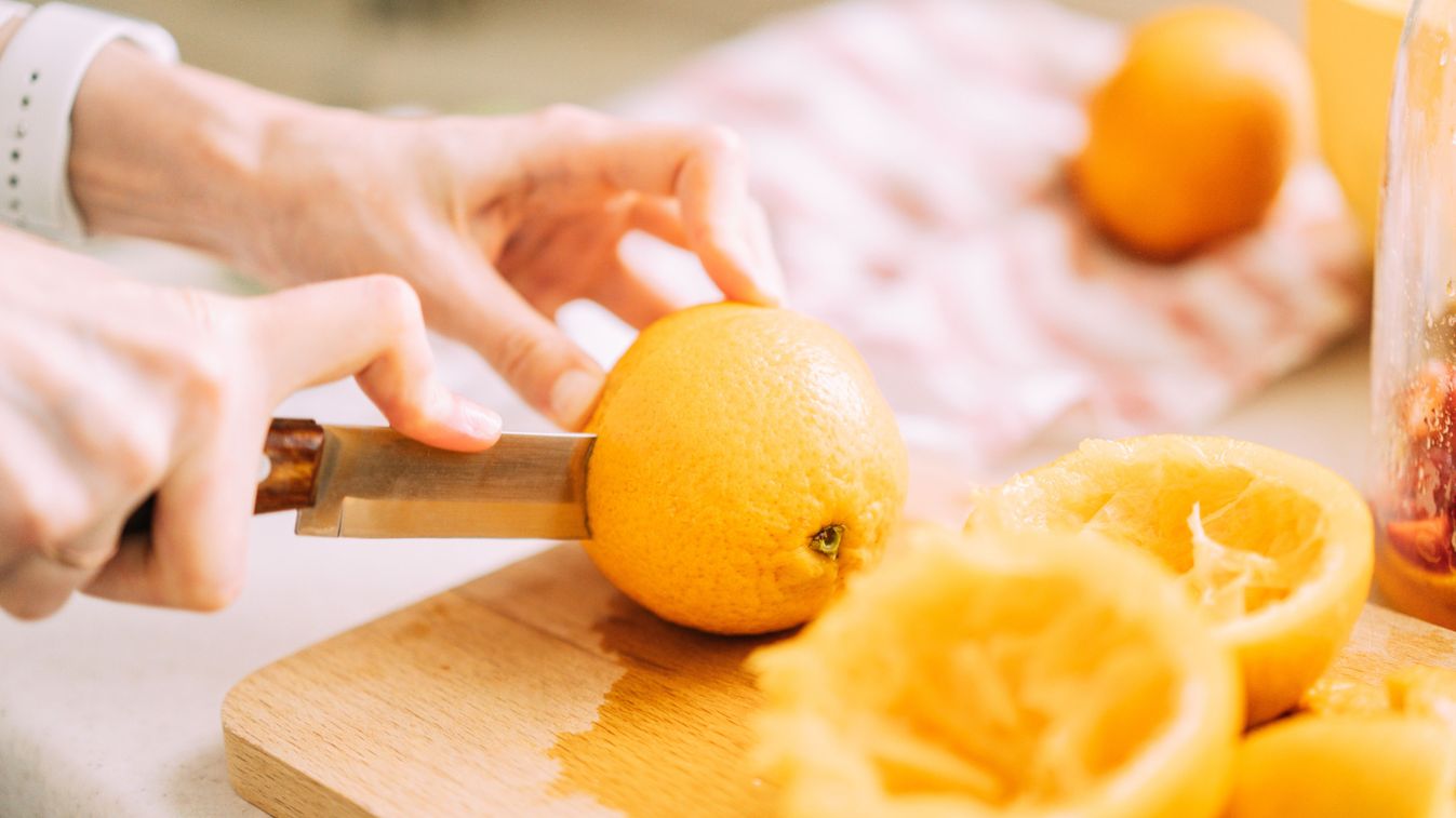 Close-up of a woman slicing oranges for cold refreshing drink