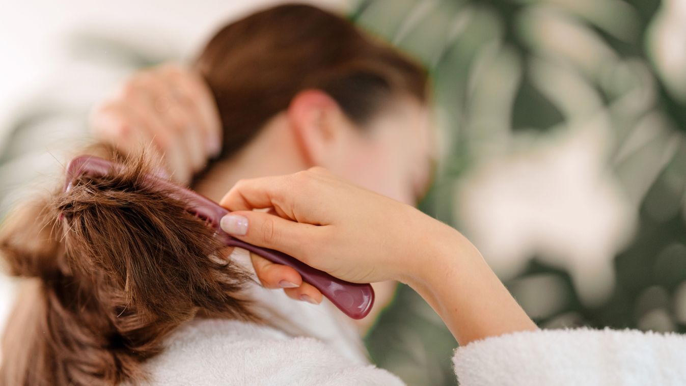 Rear view of young woman combing her hair.