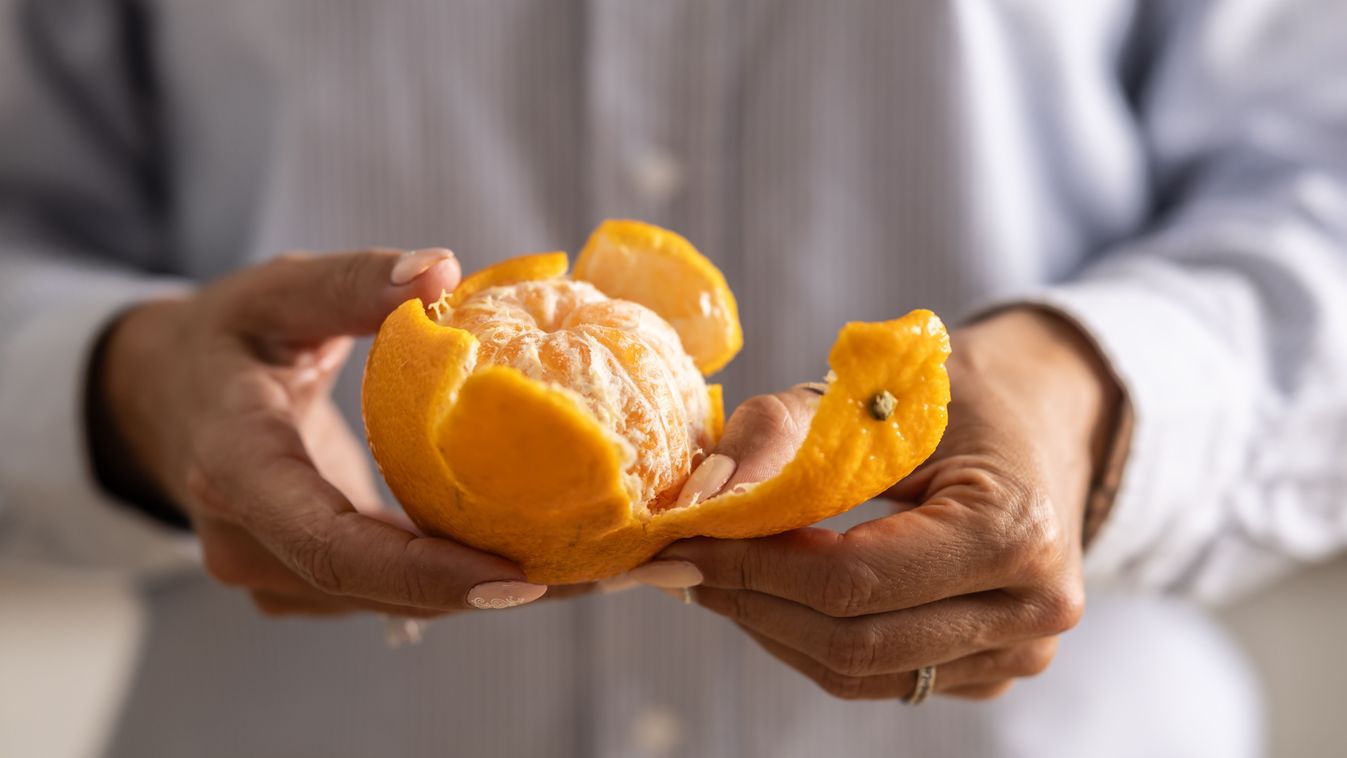 Close-up of a woman's hands peeling a tangerine.