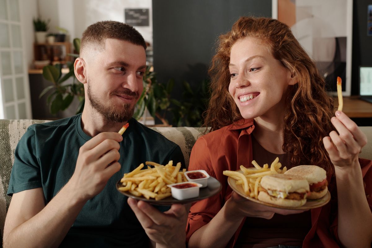 Young,Smiling,Woman,With,French,Fries,And,Hamburgers,Looking,At