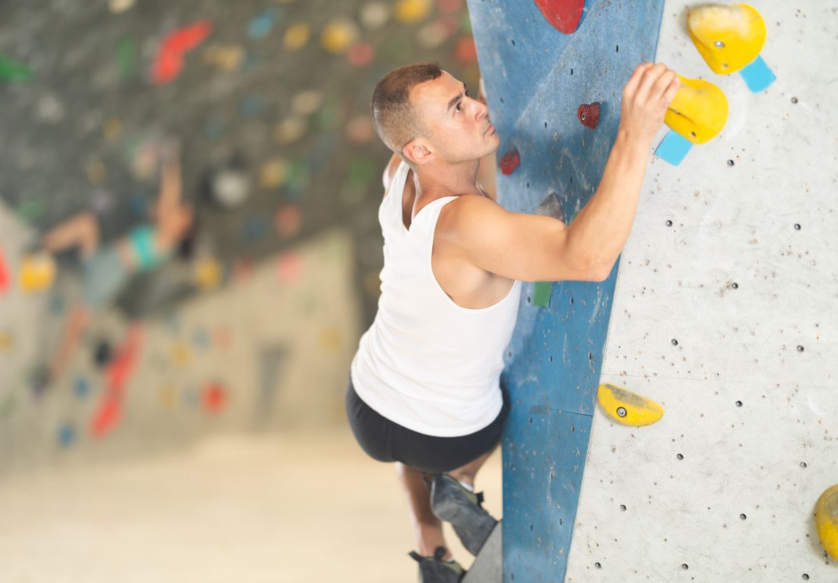 Sporty,Man,Grabbing,Ledges,Of,Artificial,Climbing,Wall,In,Bouldering