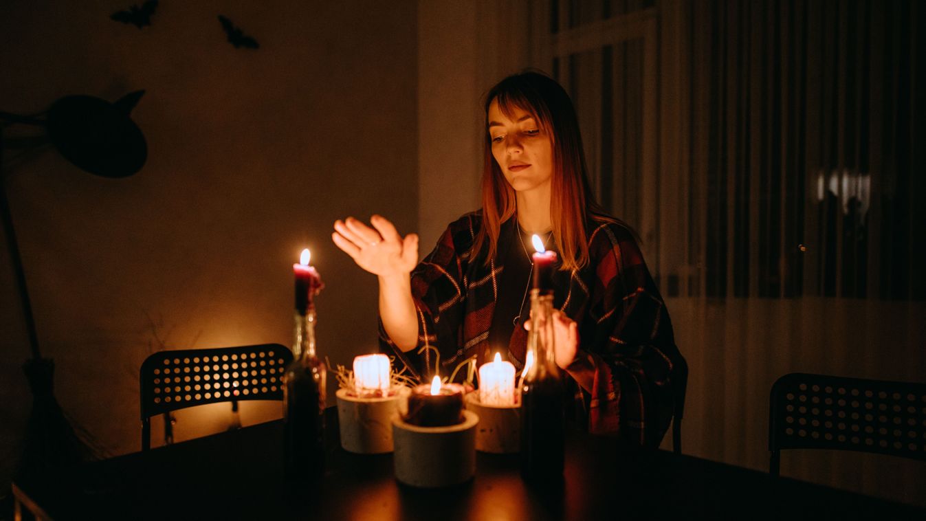 A woman conjuring on candles during Halloween In a dark stylized room