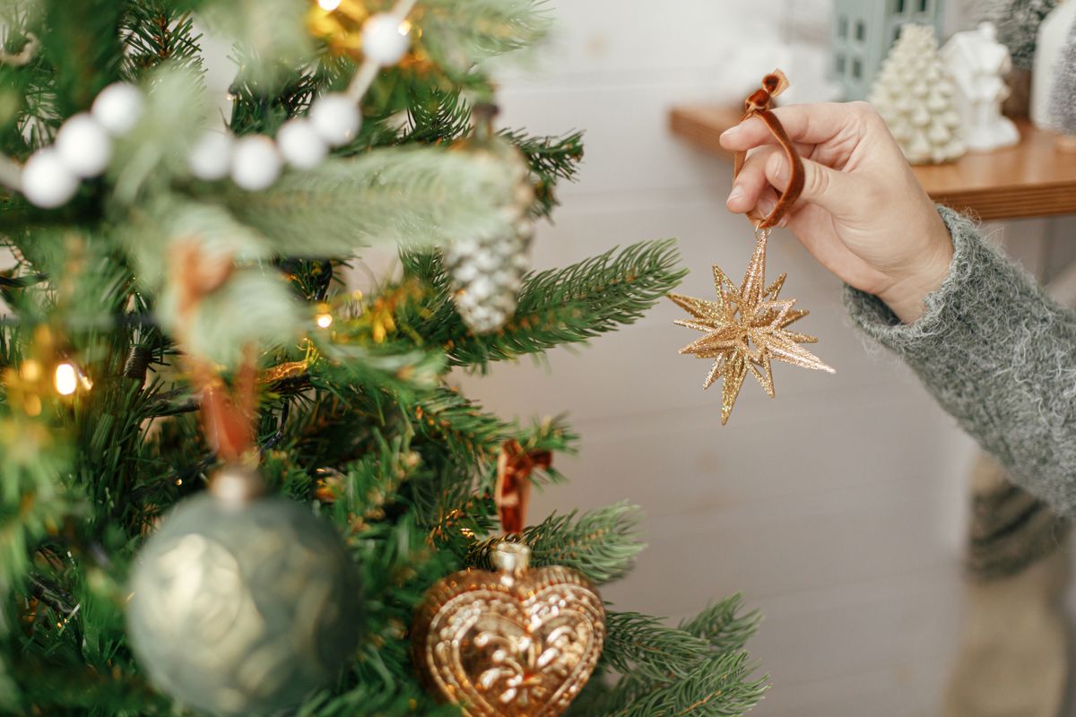 Hands,Decorating,Christmas,Tree,With,Stylish,Bauble,In,Atmospheric,Festive