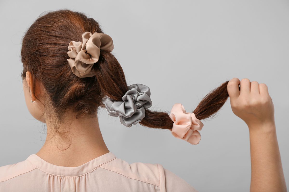 Woman,With,Silk,Scrunchies,On,Ponytail,Against,Grey,Background