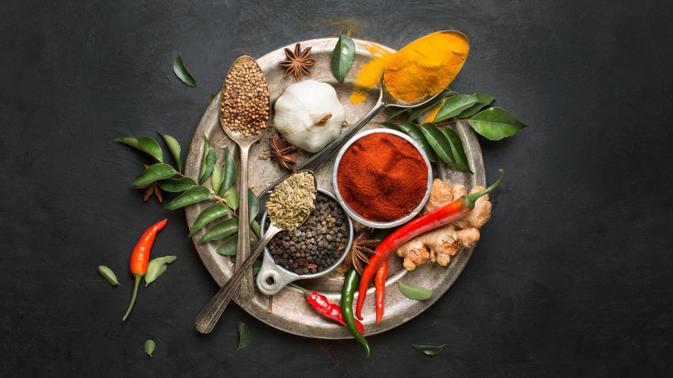 Flat lay overhead view herb and spices on textured black background.