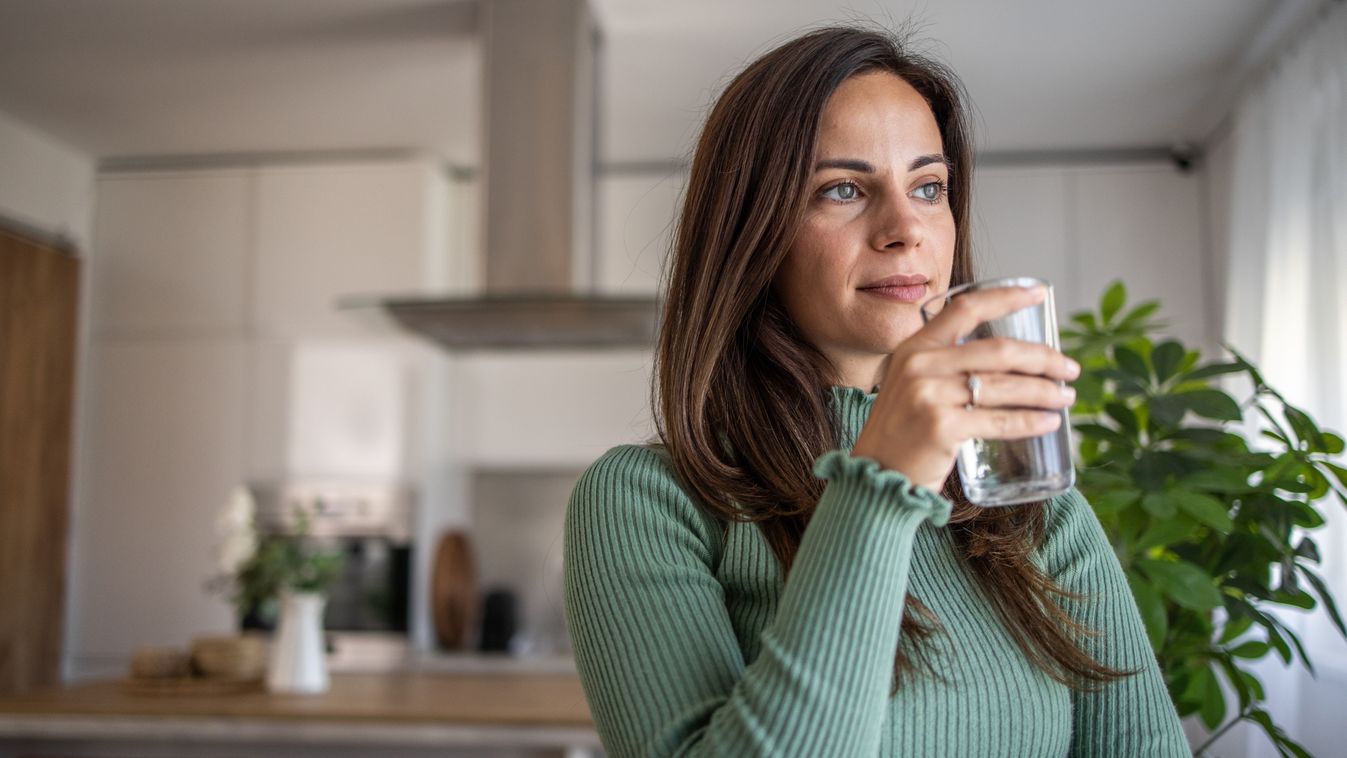 Joyful hydration: A young woman embraces a healthy life by the window.