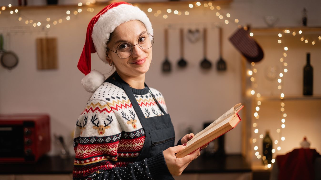 Young,Brunette,Woman,Wearing,Santa,Hat,Reading,Cookbook,In,The