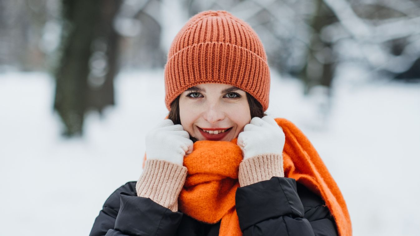 Woman,In,Orange,Winter,Hat,And,Scarf,Smiling,In,Snow-covered