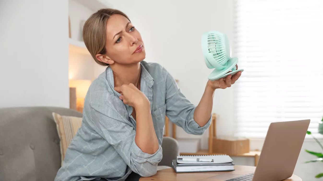 Menopause.,Woman,Using,Electric,Fan,To,Cool,Herself,During,Hot