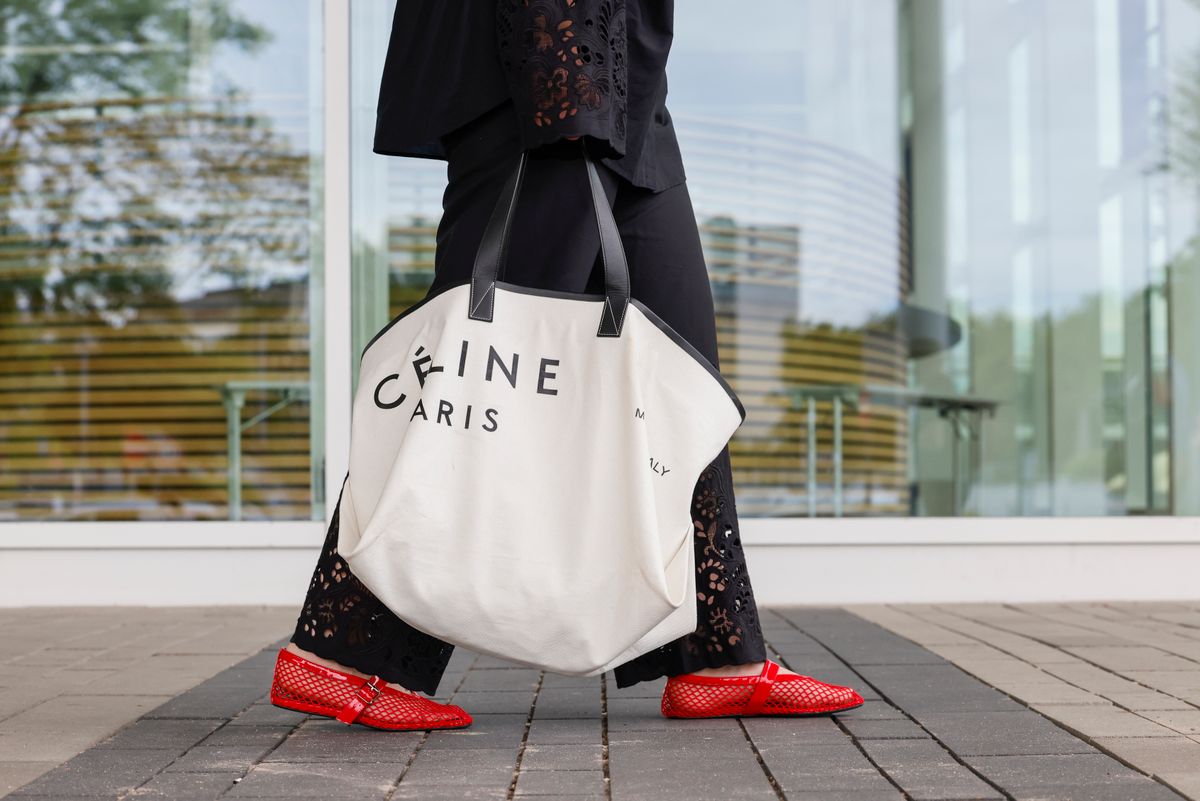 ESSEN, GERMANY - MAY 27: Influencer Maria Barteczko, wearing ablack cotton pyjama set with crochet details by Arket, a white logo canvas shopping tote bag by Celine and red fishnet ballet flats by Alaia, during a streetstyle shooting on May 27, 2024 in Essen, Germany.  (Photo by Streetstyleshooters/Getty Images)