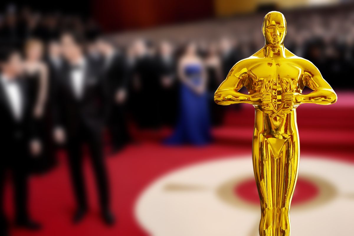 Hollywood Golden Oscar Academy award statue in the hand at the Oscars ceremony background. Success and victory concept. Oscar-díj